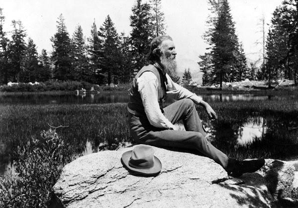 John Muir sitting on a rock in the Sierra Nevada