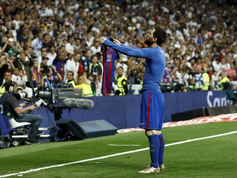 Lionel Messi holding up his jersey to the crowd at the Bernabeu
